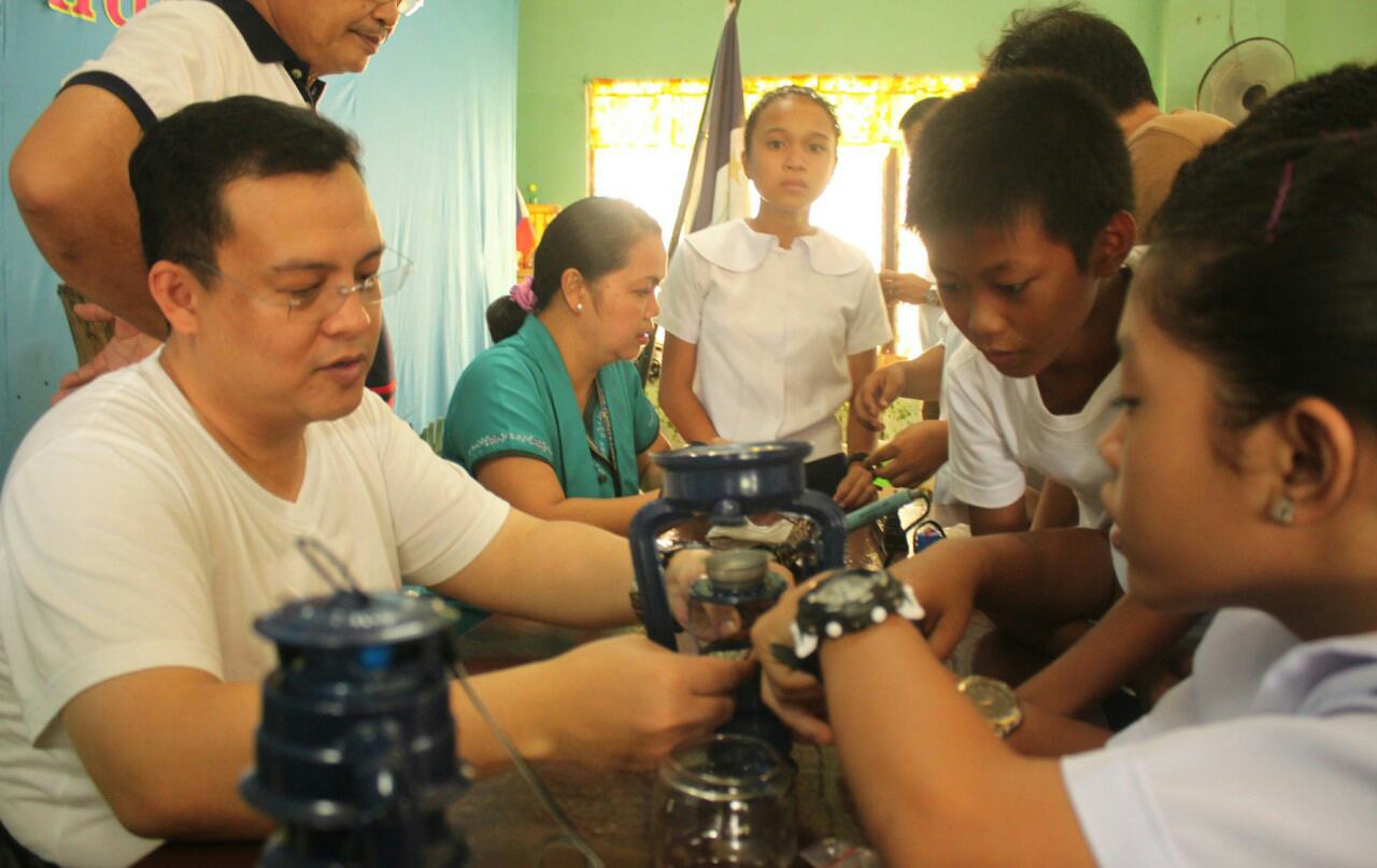 Department of Energy (DOE) Undersecretary Felix William Fuentebella (left) with Lourdes National High School Science teacher Josefina B. Maramba and Grade VI students Jillian Fuellas, Ace Roald Balbuena and Mary Joy Cuadra assemble solar-powered lamps as part of the Liter of Light orientation and training workshop of the DOE held in Panglao, Bohol on Friday, July 21, 2017.